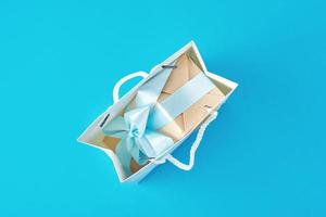 Top view inside open red paper shopping bag wirh gift box on blue background. photo