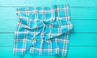 Plaid cloth background with copy space on blue wooden table. Top view and place for text photo