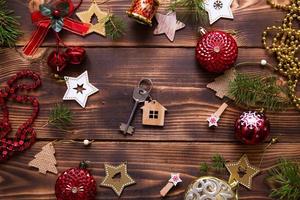 Christmas flat lay on a wooden background with keys to a new house in the center with a place for notes. New year, transfer, shares of the mortgage, the rental of a cottage. Space for text, to do list photo