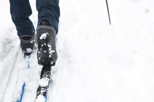 Feet of a skier in ski boots on cross-country skis. Walking in the snow, winter sports, healthy lifestyle. Close-up, copyspace photo