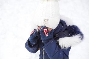Little girl crying outside in winter. A child in warm clothes is upset, cold, wipes away tears, screams, is capricious and hysterical. Winter, snow, frost, children's hysteria, discontent photo