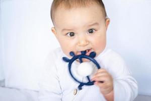 The baby is gnawing on a teething toy. Rattle scratches the gums, itching photo