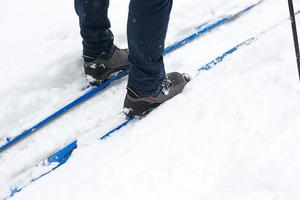 Feet of a skier in ski boots on cross-country skis. Walking in the snow, winter sports, healthy lifestyle. Close-up, copyspace photo