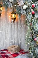 las cajas con regalos para navidad en papel kraft se encuentran en una tela escocesa roja cerca del árbol de navidad al aire libre. decoraciones de la calle de la ciudad, nieve, estado de ánimo de año nuevo, luces de hadas foto