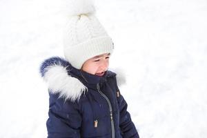 Little girl crying outside in winter. A child in warm clothes is upset, cold, wipes away tears, screams, is capricious and hysterical. Winter, snow, frost, children's hysteria, discontent photo