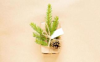 Gift box for Christmas and new year in eco-friendly materials kraf paper, live fir branches, cones, twine. Tags with mock up, natural decor, hand made, DIY. Flatly, background, frame, Minimalism photo