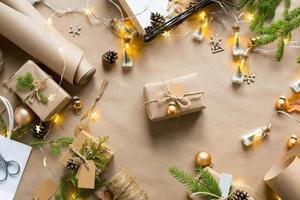 Pack a gift for Christmas and new year in eco-friendly materials kraft paper, live fir branches, cones, twine. Tags with mock up, natural decor, hand made, DIY. Festive mood. Christmas background photo