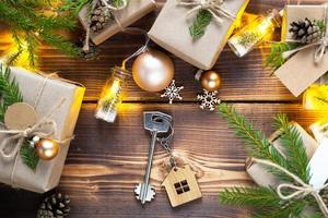 la llave de la casa sobre un fondo natural con una caja con un regalo para navidad y año nuevo. vivienda ecológica, hipoteca, préstamo, reserva, compra de bienes inmuebles, mudarse a su casa