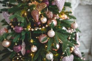 Christmas decorations on a fir tree close-up. Toys, cones, garlands with lights, balls, beads. New year, festive background. photo