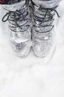 The boots on the laces are covered with snow. Winter, snowfall, cold, felted wool shoes, frost protection, frost resistance. Life in the village, cottage core, authenticity. Close-up, copyspace photo