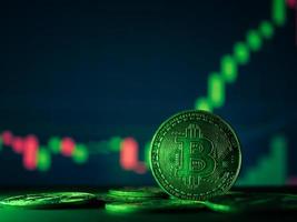 Coins with bitcoin symbol on green light and crypto stocks chart background. photo