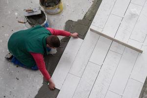 worker installing the ceramic wood effect tiles on the floor photo