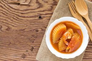 Sour curry shrimp and papaya on wood background photo