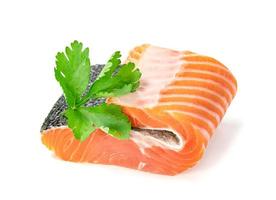 Piece of fresh salmon fillet sliced with coriander leaves isolated on white background photo