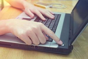 encienda el interruptor de la computadora portátil en el escritorio, el hombre del primer plano que usa el cuaderno en la mesa de madera foto