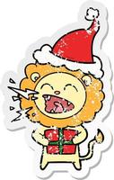 distressed sticker cartoon of a roaring lion with gift wearing santa hat vector