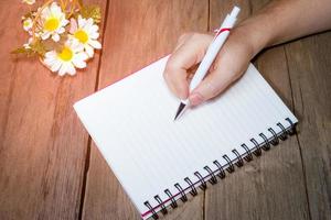 Human hand holding pen with open note book photo