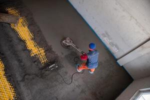 trabajador realizando y puliendo suelo de solera de cemento y arena foto