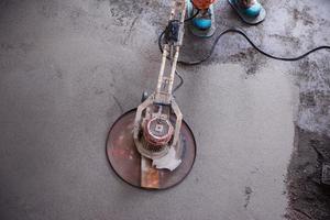 worker performing and polishing sand and cement screed floor photo