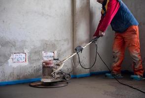 worker performing and polishing sand and cement screed floor photo