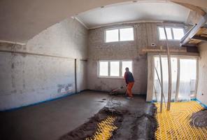 worker performing and polishing sand and cement screed floor photo