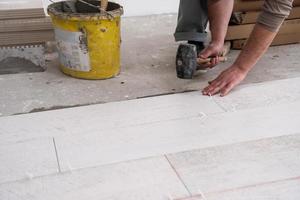 worker installing the ceramic wood effect tiles on the floor photo