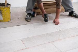 worker installing the ceramic wood effect tiles on the floor photo