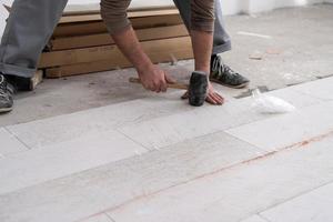 worker installing the ceramic wood effect tiles on the floor photo