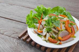 Thai cuisine spicy pork salad on wood background or Yum Moo Yor photo