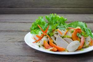 Thai cuisine spicy pork salad on wood background or Yum Moo Yor photo