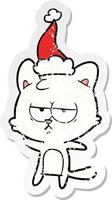 bored distressed sticker cartoon of a cat wearing santa hat vector