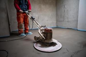 worker performing and polishing sand and cement screed floor photo