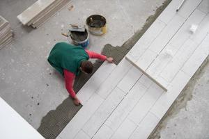 worker installing the ceramic wood effect tiles on the floor photo