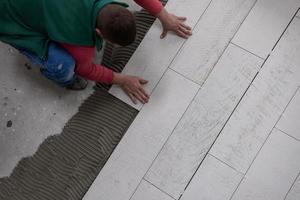 worker installing the ceramic wood effect tiles on the floor photo