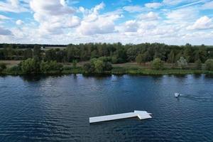 bellas imágenes de la cámara de drones aéreos del lago y parque willen que se encuentra en milton keynes, inglaterra. la gente está disfrutando en el lago en un caluroso día soleado de verano foto