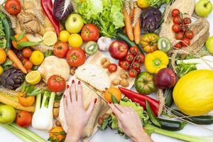 Flat photo of a woman cutting bread on a table with vegetables