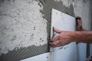 trabajador instalando grandes baldosas de cerámica foto