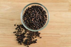Black pepper in a glass bowl on the wooden table. food, spice, seasoning Concept. photo