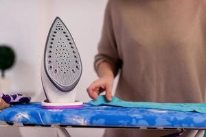 Red haired woman ironing clothes at home photo