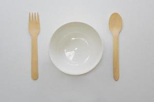 Empty ceramic white bowl and wooden spoons, wooden forks on white background,Top view.