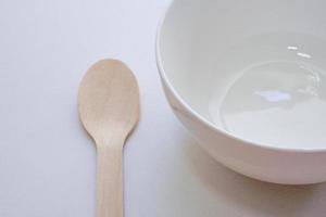 Empty ceramic white bowl and wooden spoons, wooden forks on white background,Top view. photo