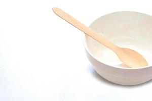 cuenco blanco de cerámica vacío y cucharas de madera, tenedores de madera sobre fondo blanco, vista superior. foto