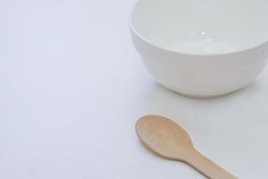 cuenco blanco de cerámica vacío y cucharas de madera, tenedores de madera sobre fondo blanco, vista superior. foto