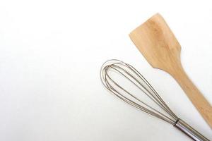 Top view kitchen equipment, egg beater and wooden spatula on white background. photo