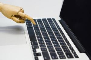 Selective focus of robot finger is using a laptop. Concept of artificial intelligence, technology and progress future. photo