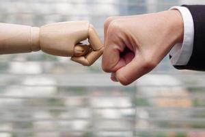 Clash of fists between businessman hand and robot hands. Concept of Artificial intelligence, teamwork, join forces, progress future and competition. photo