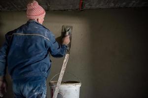 trabajador enyesando la pared con hormigón foto