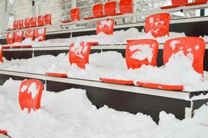 Red stadium seats covered with snow. photo