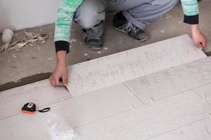 worker installing the ceramic wood effect tiles on the floor photo