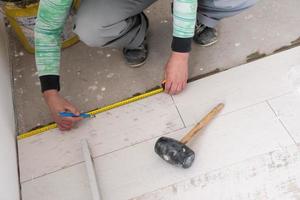 worker installing the ceramic wood effect tiles on the floor photo